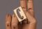 Wooden jointed hand holding a beige block with the letter C on it. Minimalist and artistic composition.